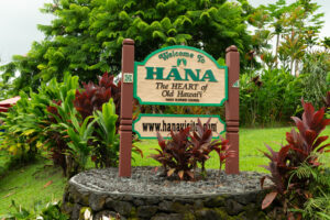 A green roadside sign that reads “Welcome to Hana,” marking the entrance to the town at the end of Maui’s iconic Road to Hana scenic drive.