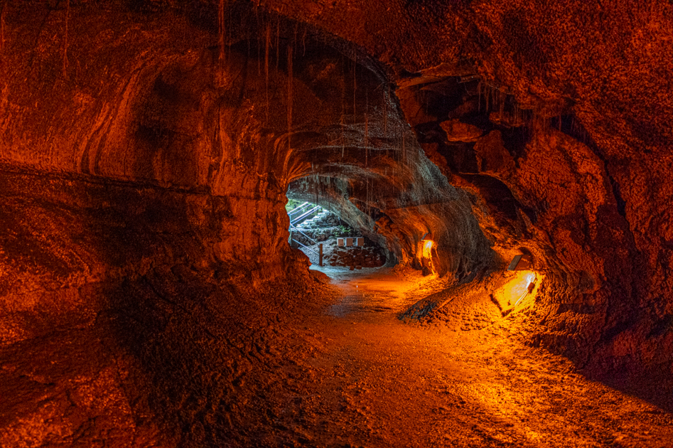 Interior of the Thurston Lava Tube in Hawaiʻi Volcanoes National Park showing smooth, dark lava walls and a dimly lit tunnel path. travel photography. travel blogs, travel photography, photography travel blog, back roads lens