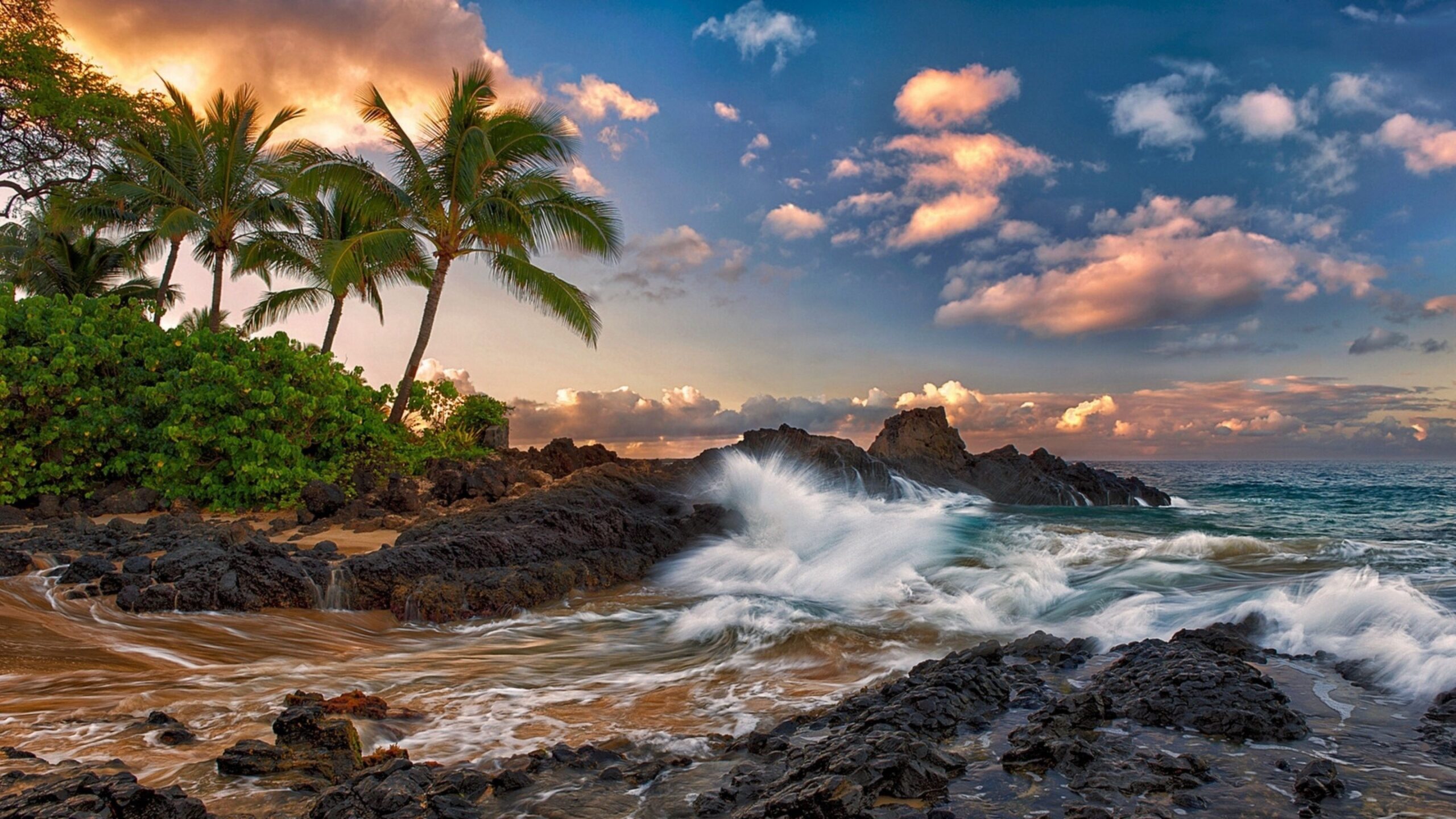 Golden sunset over an ocean beach with black lava rocks and waves crashing onto the shore.Leica Q3 travel camera