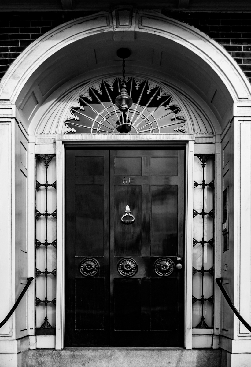 Black-and-white image of a weathered stone arch with a dark wooden door in Belize.