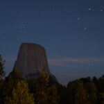 Devil’s Tower silhouetted against a star-filled night sky in Wyoming.Devil’s Tower under a starry sky, captured in a long-exposure photograph.