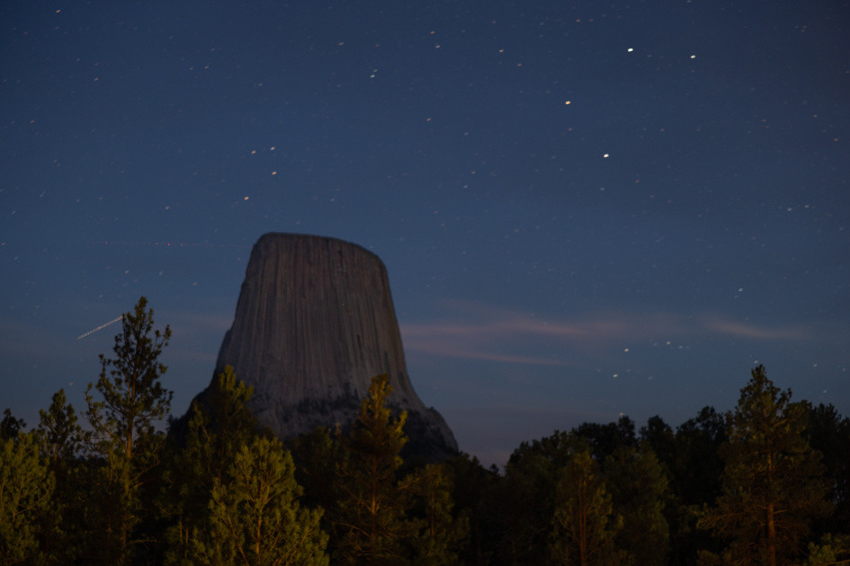 Devil’s Tower silhouetted against a star-filled night sky in Wyoming.Devil’s Tower under a starry sky, captured in a long-exposure photograph.