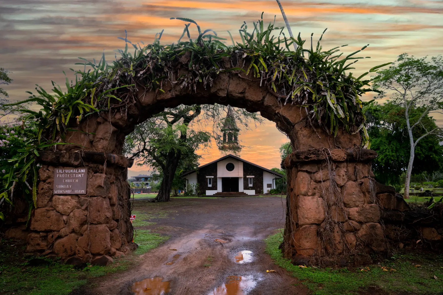 stone arch framing an old church in Haleawa Hawaii with the sunset in the background
