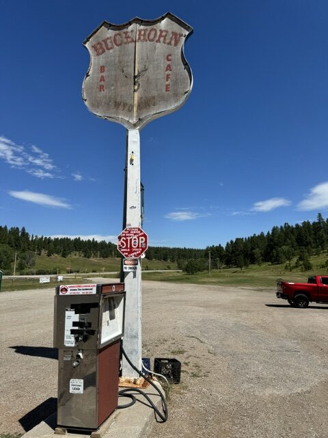 Exterior of Buckhorn Bar and Grill in Buckhorn, Wyoming, featuring a vintage gas pump and weathered sign under open skies