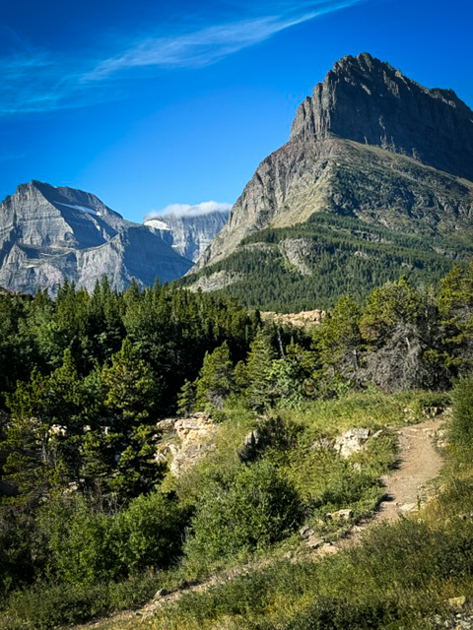 Towering mountain peaks in Glacier National Park under a clear blue sky with rugged alpine terrain