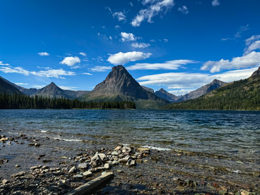 Two Medicine Lake with calm water reflecting surrounding mountains and sky in Glacier National Park