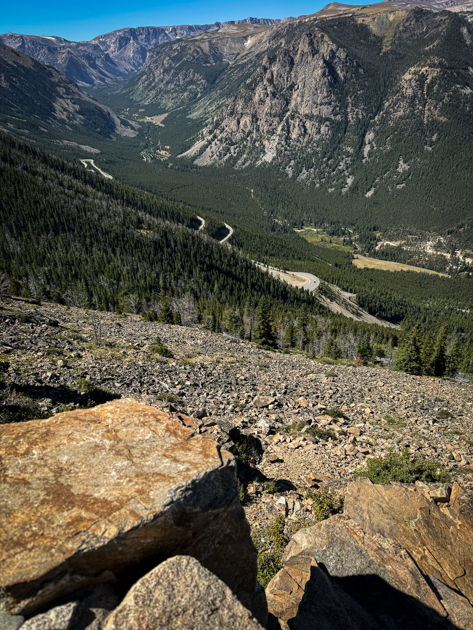View of the Beartooth Highway winding through alpine mountains with rocky terrain and clear blue sky.