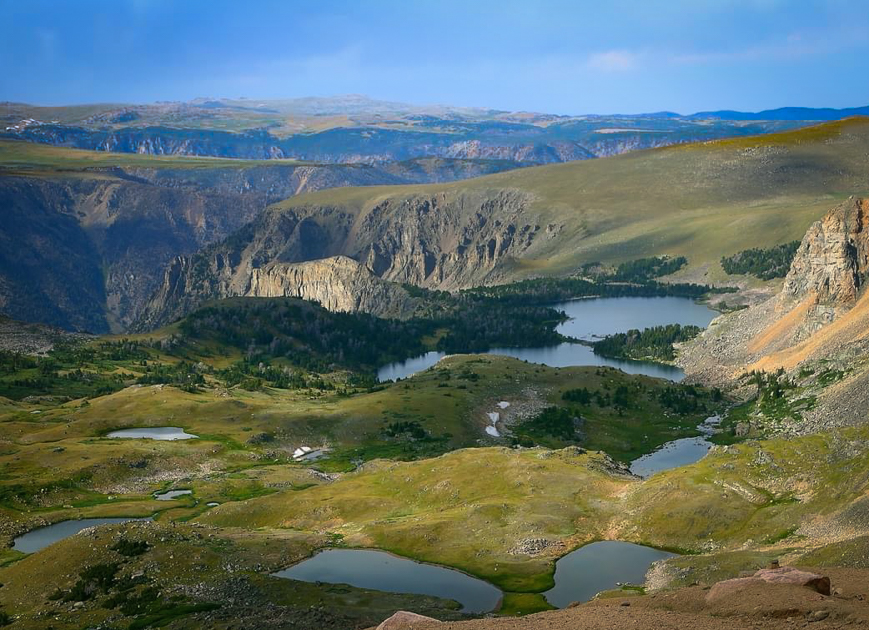 Scenic view of alpine lakes along the Beartooth Highway surrounded by rocky mountains and clear blue skies.