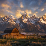 John Moulton Barn on Mormon Row with snow on the Teton Mountains and a colorful sky in Grand Teton National Park.Back roads travel and photography blog. travel guides