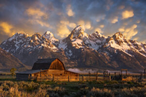 John Moulton Barn on Mormon Row with snow on the Teton Mountains and a colorful sky in Grand Teton National Park.Back roads travel and photography blog
