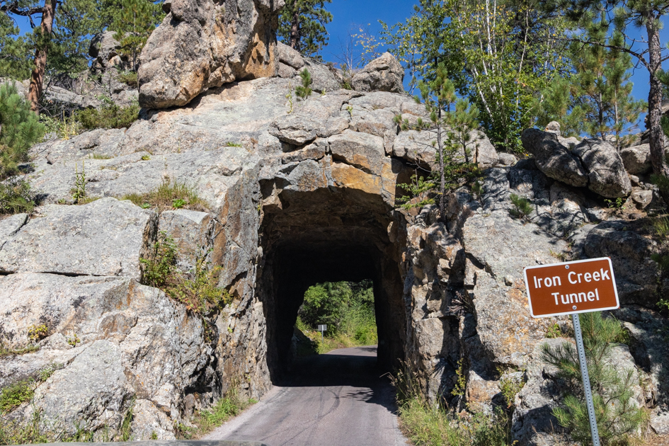 View through Iron Creek Tunnel framing the winding road and granite landscape in Custer State Park, South Dakota