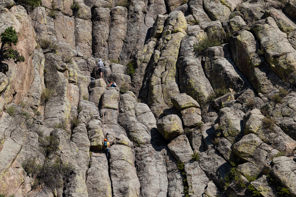 Two climbers scaling the natural columnar rock formations of Devil’s Tower, highlighting adventure and geology