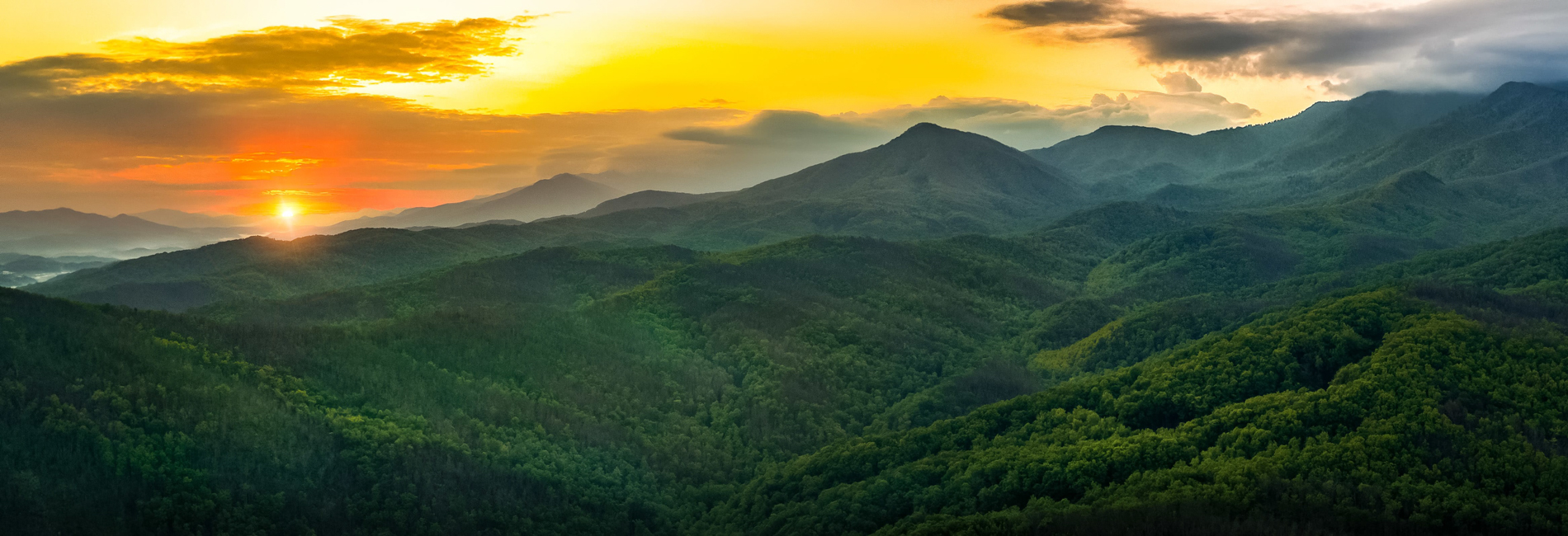 Panoramic sunrise view of the Smoky Mountains with fog in the valleys.