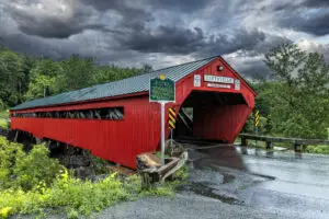 red covered bridge with stormy skiis in the background