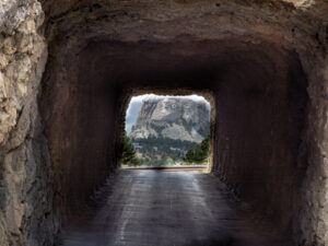 Distant view of Mount Rushmore aligned through Shovel Johnson Tunnel on a scenic drive in Custer State Park