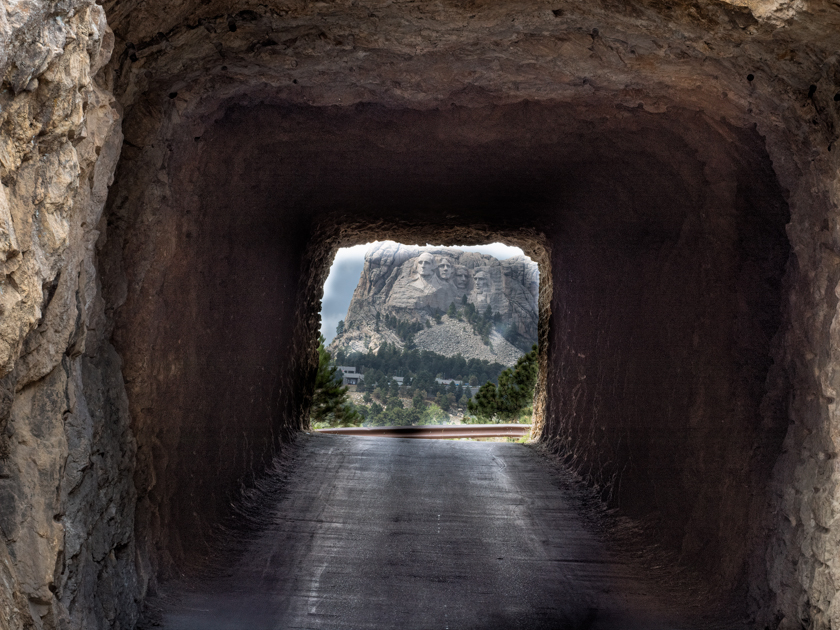 Distant view of Mount Rushmore aligned through Shovel Johnson Tunnel on a scenic drive in Custer State Park