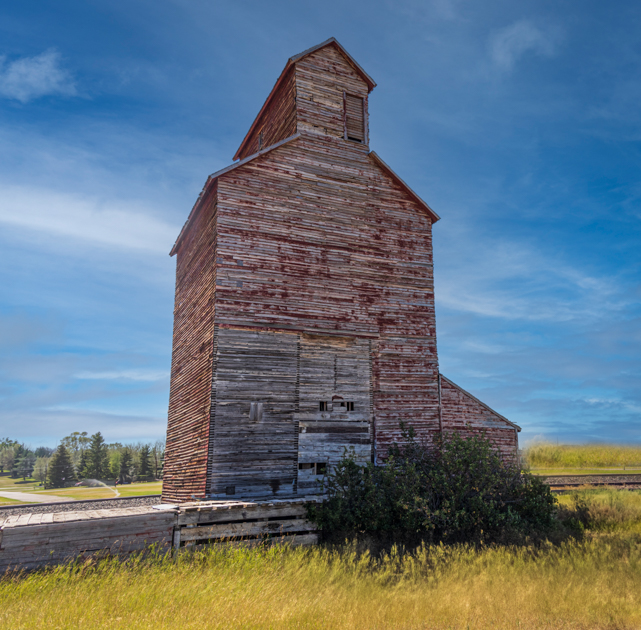 Weathered wooden grain silo in a rural Montana field, captured during a Back Roads Lens photography road trip