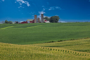 Red barn and rural farm surrounded by multiple fields of crops in the Iowa countryside