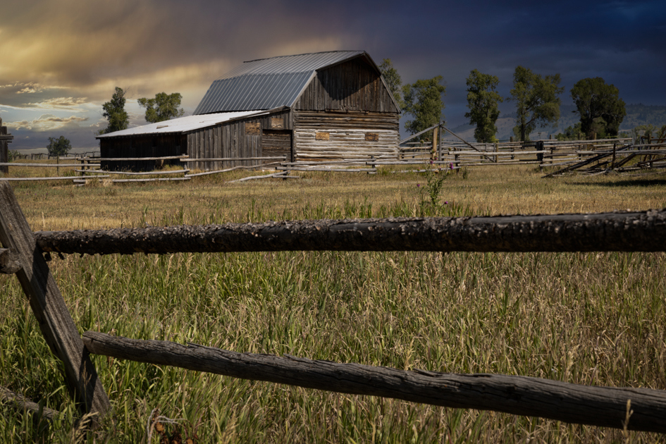 Historic barn at Mormon Row with a rustic wooden fence in the foreground and the Teton Range in the background
