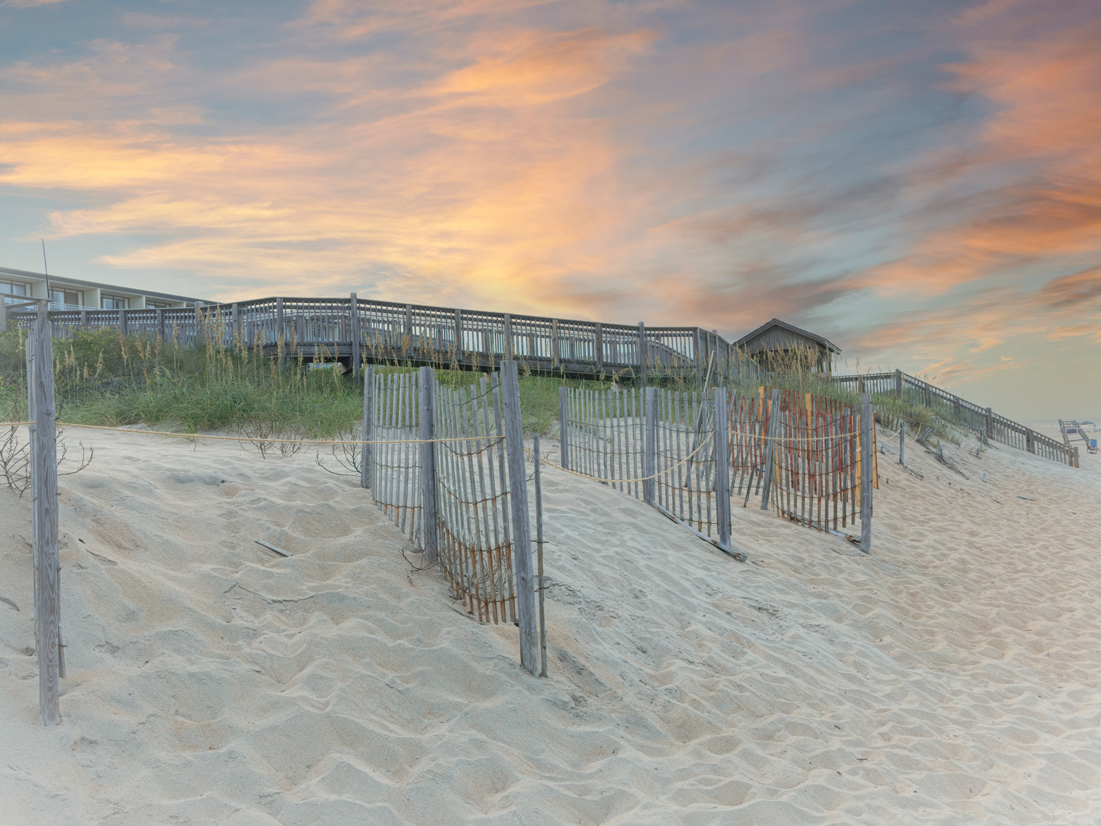Outer Banks beach at sunset with wooden walkways, sand fences, and dunes leading to the ocean. seascape photography