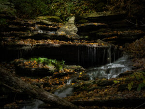 Small waterfall surrounded by colorful fall leaves on rocks in the Adirondack Mountains of New York