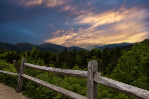 view of mountains at sunset with a rustic fence in the foreground