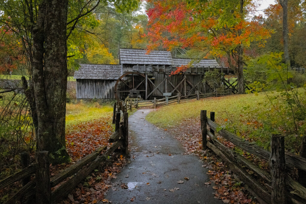 view of Mabry Mill reflecting in the still water, surrounded by vivid autumn leaves along the Blue Ridge Parkway.