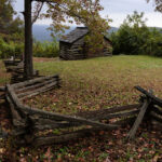 Historic trail cabin along the Blue Ridge Parkway in North Carolina, surrounded by trees and mountain scenery