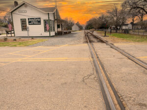 Sunset behind the historic train depot in Plains, Georgia, casting warm golden light on the red brick building.
