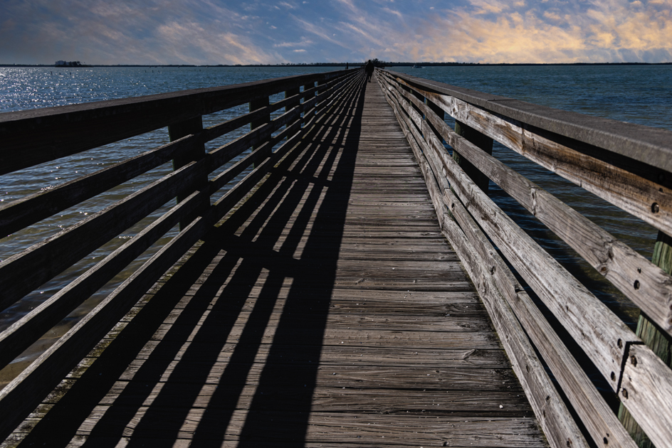 Scenic view of the Dunedin Pier extending into the calm waters of the Gulf of Mexico at sunset
