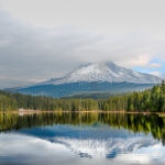 Trillium Lake with Mount Hood reflected under a moody, cloudy sky, creating a serene atmosphere.