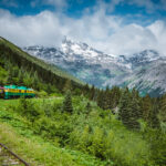 White Pass and Yukon Route Railroad train rounding a curve with Alaskan mountains in the background