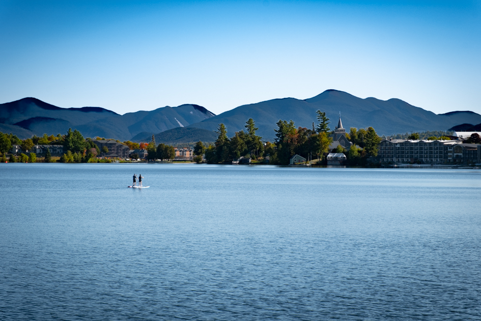 Mountains surrounding Mirror Lake in Lake Placid, New York, with calm waters in the foreground.
