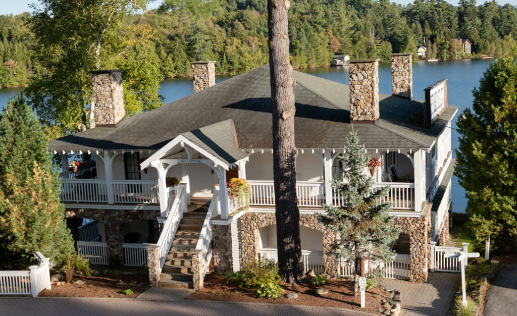 Cottage at Mirror Lake Inn in Lake Placid, New York, surrounded by greenery.
