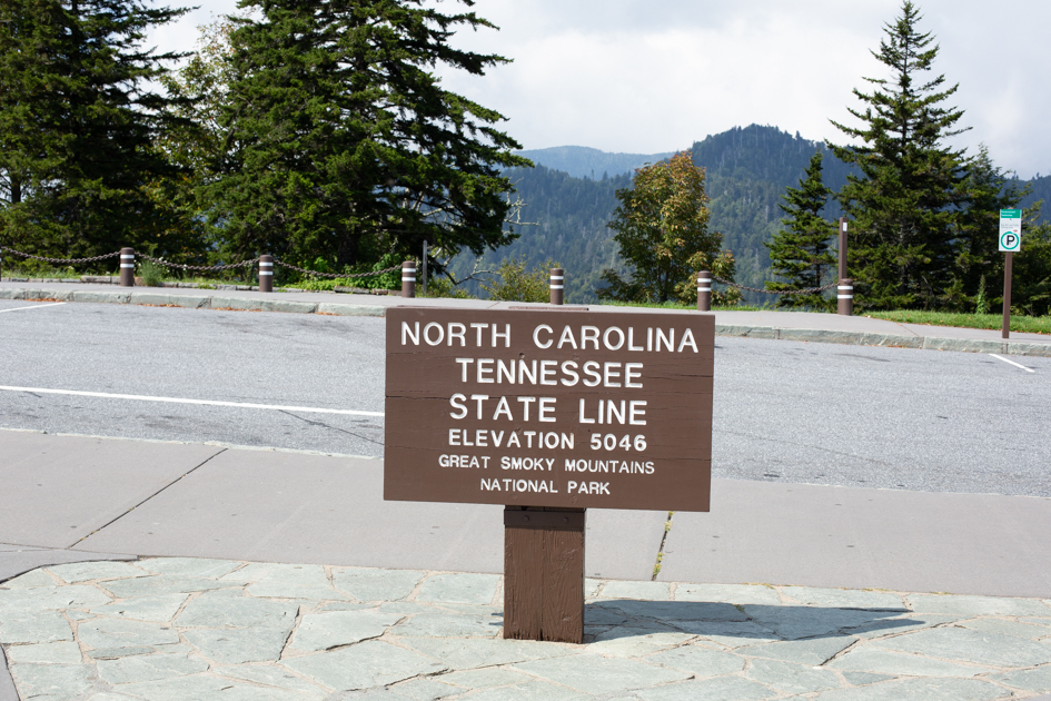 Wooden marker showing the state line between North Carolina and Tennessee within the Smoky Mountains National Park.