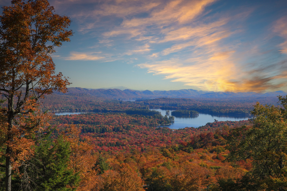 Aerial photograph of the Adirondack Mountains and lakes surrounded by vibrant fall foliage in shades of red, orange, and yellow.