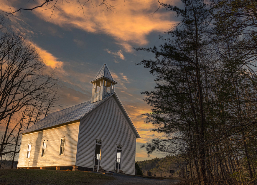 White Primitive Baptist Church in Cades Cove with wooden benches inside.