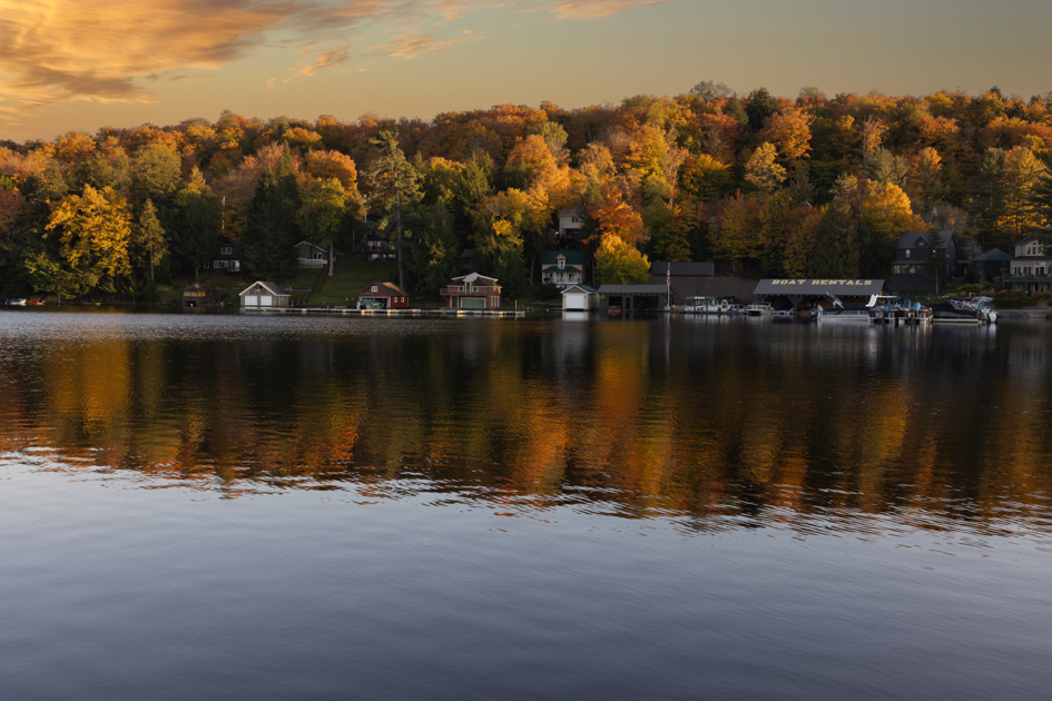 Lake in Old Forge, New York, surrounded by colorful autumn trees reflecting on the water.