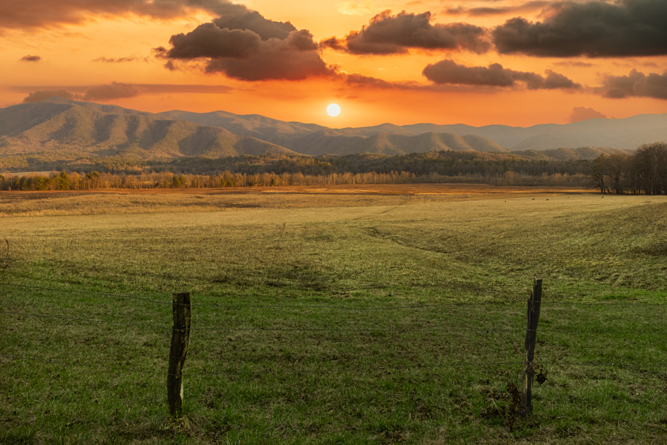 Rolling mountains rise beyond the wide open fields of Cades Cove in Smoky Mountains National Park.