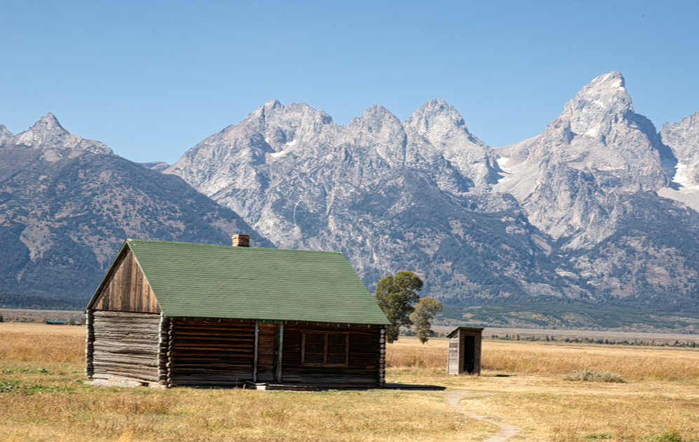A weathered wooden cabin on Mormon Row surrounded by sagebrush with the Teton Range in the background, Grand Teton National Park
