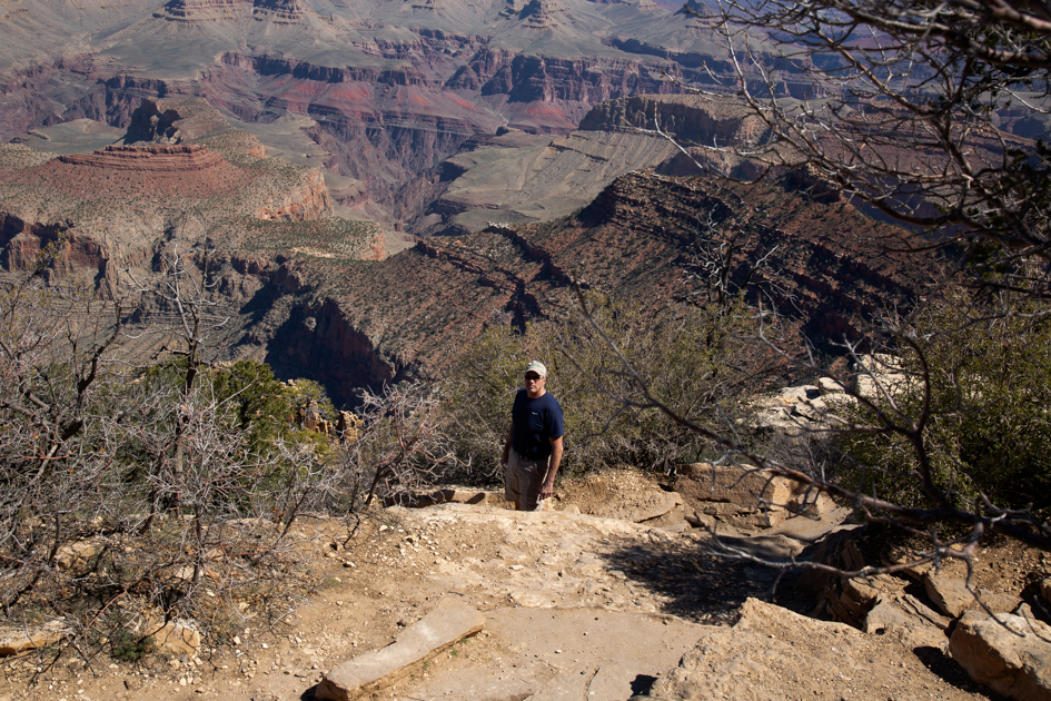 Hiker beginning the descent into the Grand Canyon along a winding trail with towering canyon walls