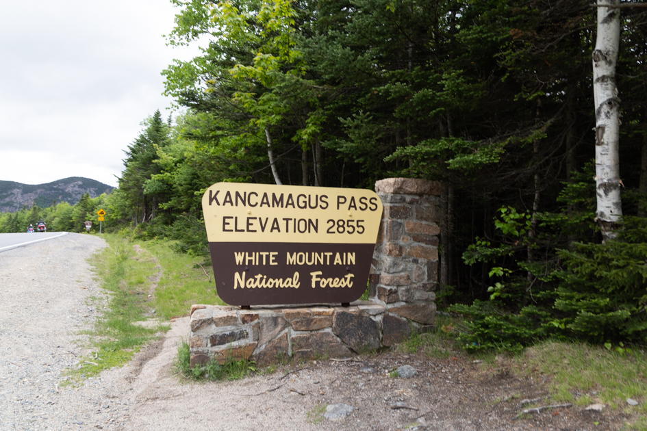 Wooden Kancamagus Pass sign along the scenic highway in New Hampshire’s White Mountains on a bright summer day