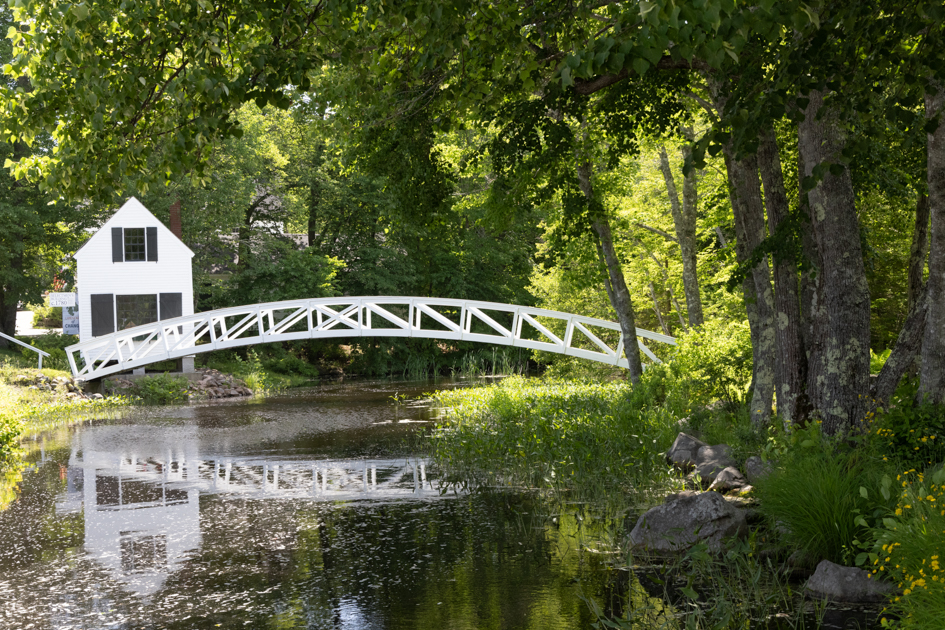 White wooden Somesville Bridge reflected in the still pond on a calm morning in Mount Desert Island, Maine.
