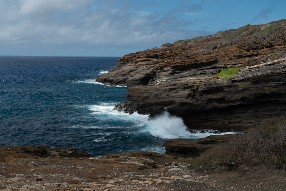 view from Makapuʻu Point Lighthouse perched on a rocky cliff above turquoise Pacific waters on Oahu’s southeastern shore.
