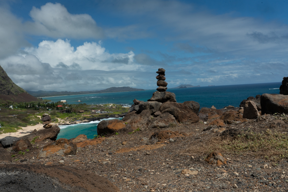 Coastal view looking back toward Makapuʻu Beach with waves breaking along the shore and cliffs rising behind.
