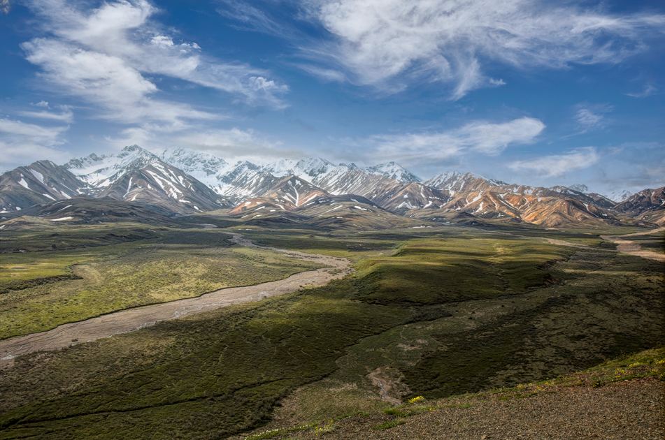 Snow-capped peaks and tundra reflected in a calm alpine lake in Denali National Park
