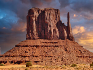 West Mitten Butte in Monument Valley glowing in late afternoon light, its red sandstone silhouette rising above the desert floor.