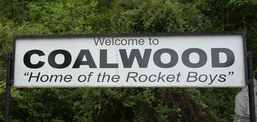 Welcome sign for Coalwood, West Virginia reading “Home of the Rocket Boys” beside a quiet Appalachian roadside.
