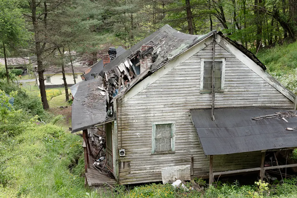 Weathered abandoned house along a narrow road in a rural Appalachian holler.