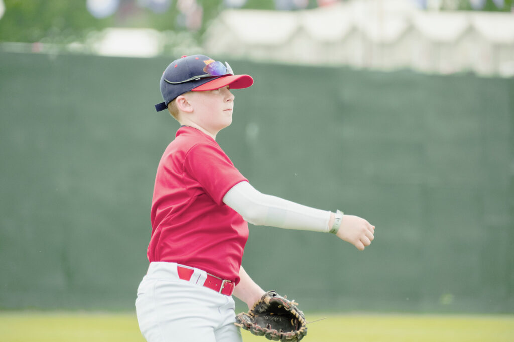 Youth baseball player throwing the ball during a game at Cooperstown Dreams Park.
